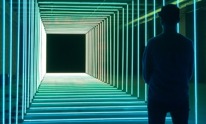 Tunnel of lights in a box shape with a man standing at the top of the tunnel looking down 