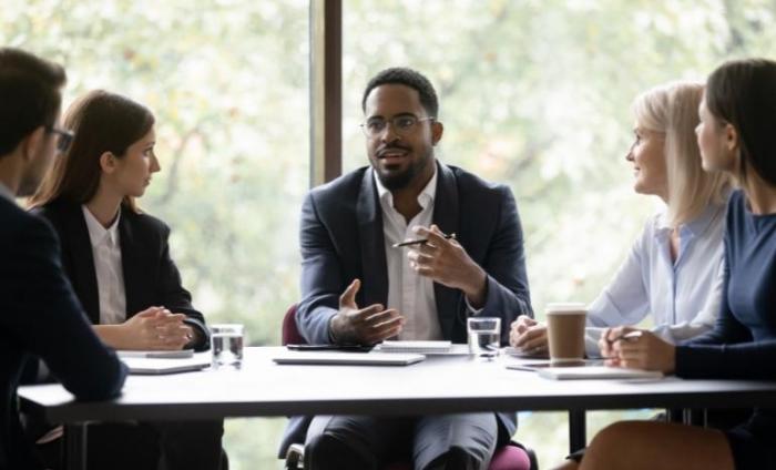 Group in a business meeting with the focus on one man addressing the group.