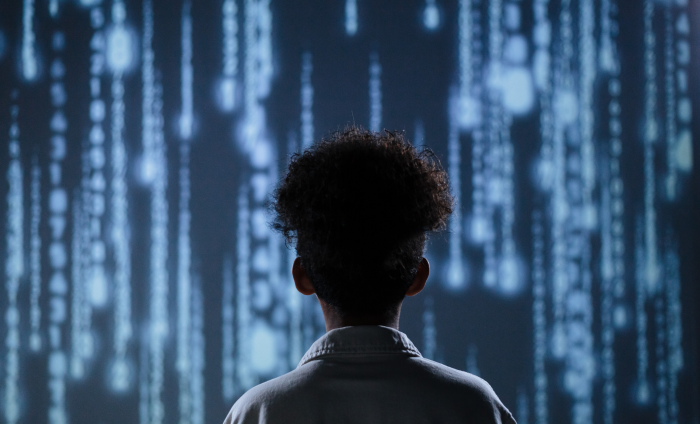 A child looks at a screen of lights and code